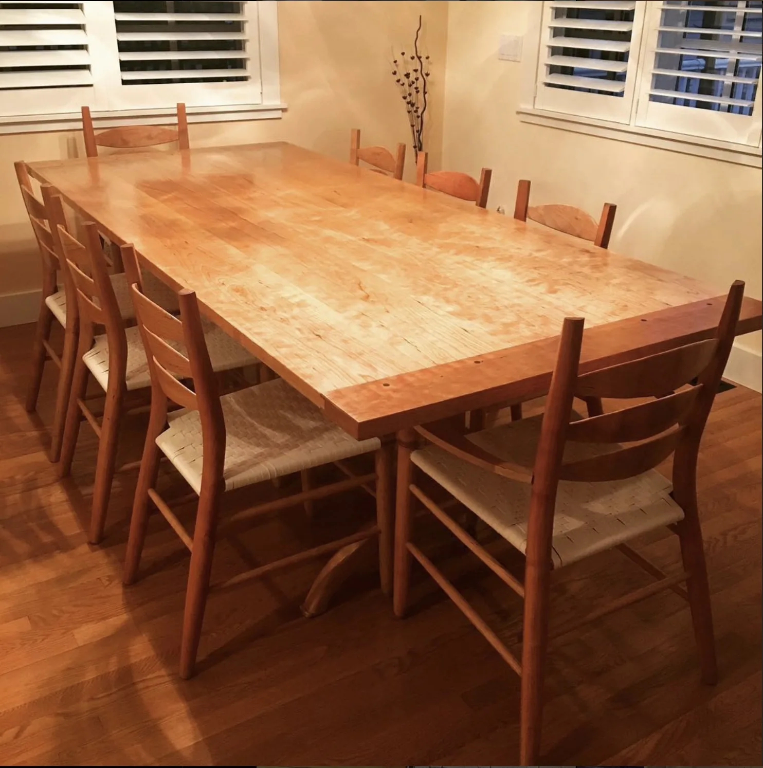 Handcrafted cherry dining table with ladder-back chairs and woven seats, built by Rew Construction