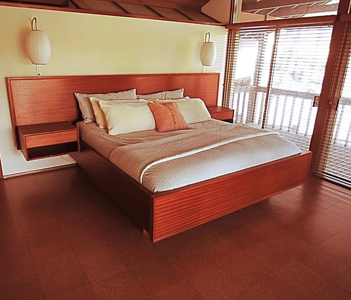 Custom platform bed with floating nightstands and full-width wood headboard by Rew Construction