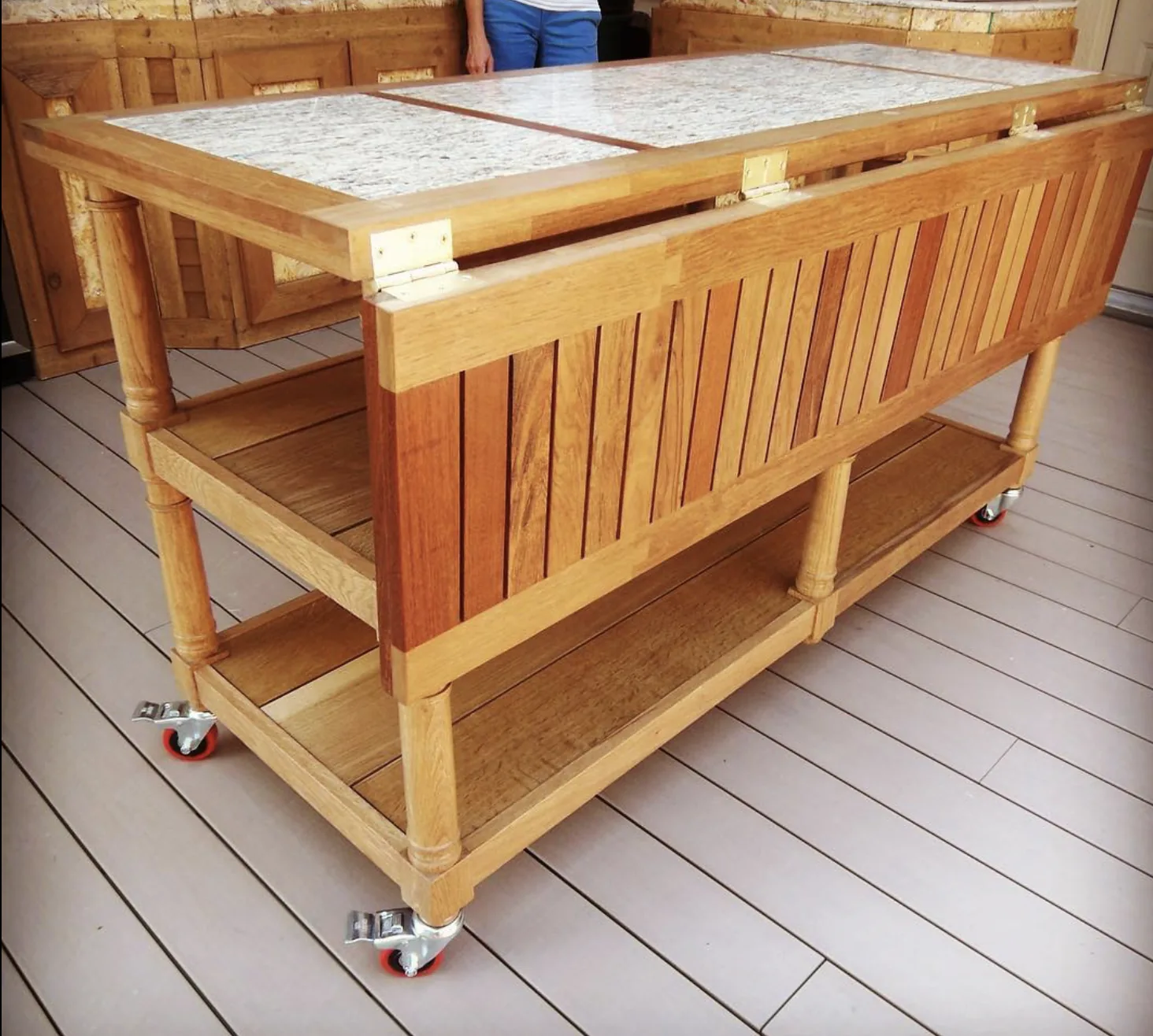 Rolling outdoor kitchen cart with granite top and slatted wood sides, handcrafted by Rew Construction